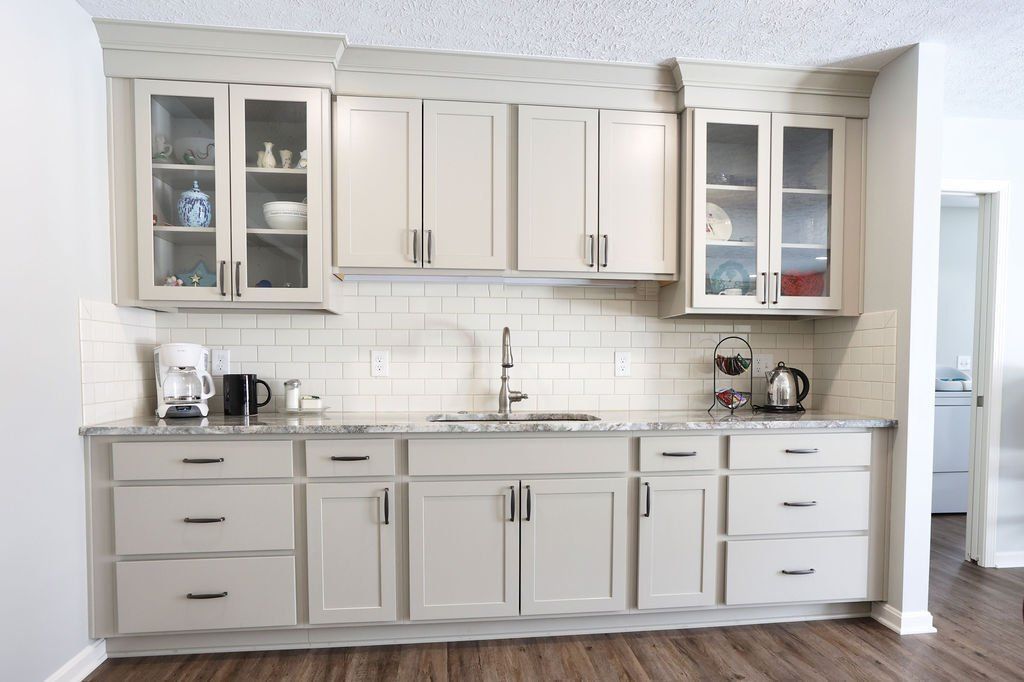 Beige kitchen with cabinets, a sink, and a white tile backsplash.