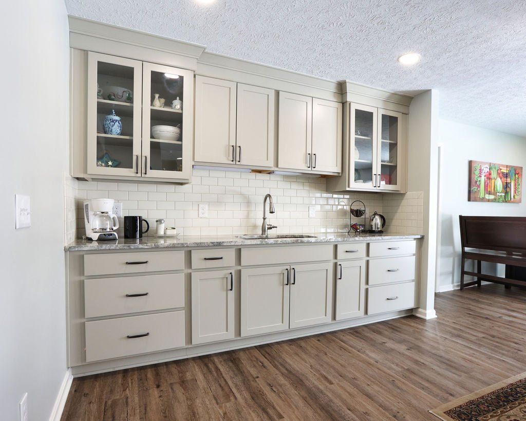 Beige kitchen cabinets with a gray countertop and a tiled backsplash.