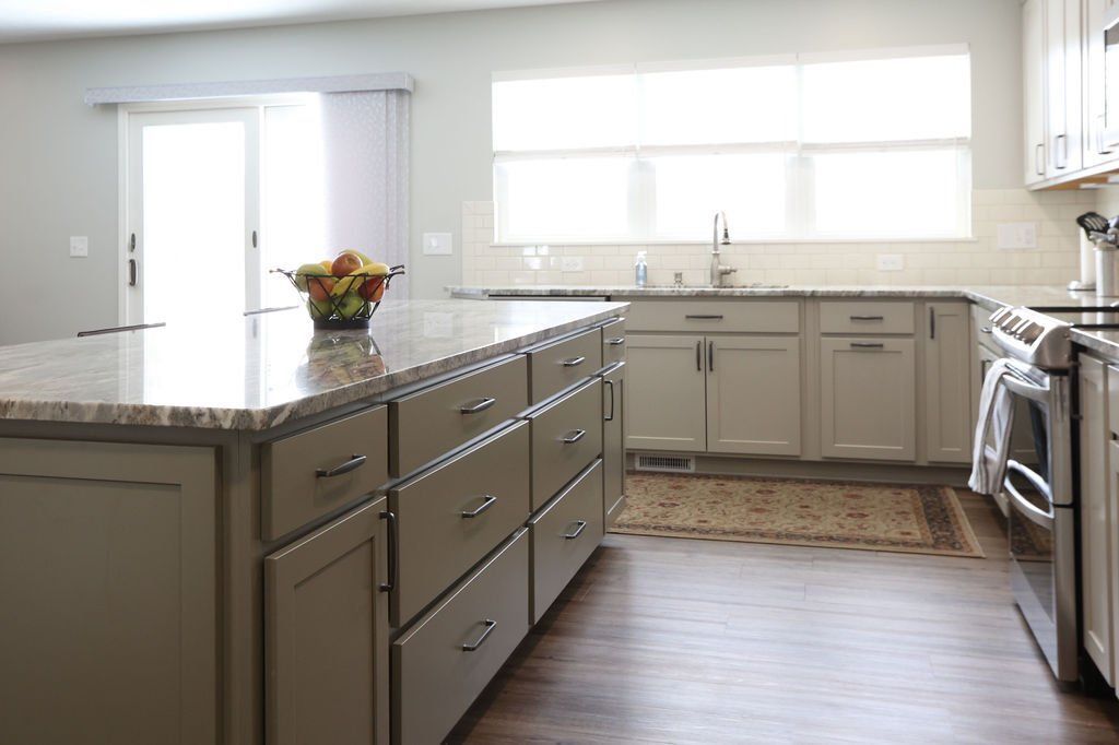 Kitchen with grey cabinets, granite countertops, and fruit bowl on island.