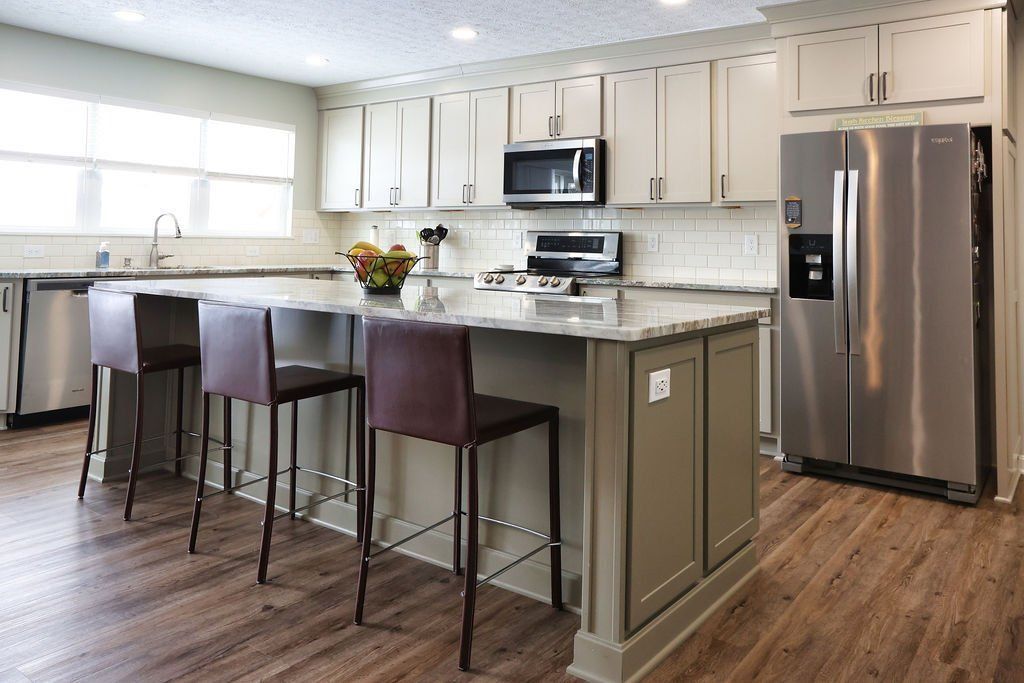 Modern kitchen with island, bar stools, white cabinets, and stainless steel appliances