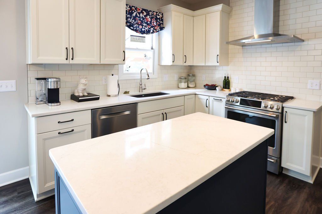 White kitchen with blue island, stainless steel appliances, and white countertop.