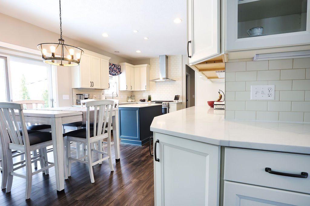 Bright kitchen with white cabinets, island seating, dark floors, and a view into the dining area.