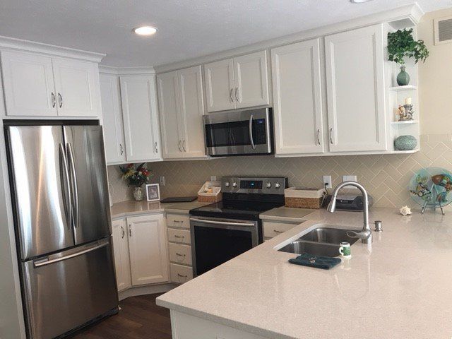 White kitchen with stainless steel appliances and light-colored countertops.