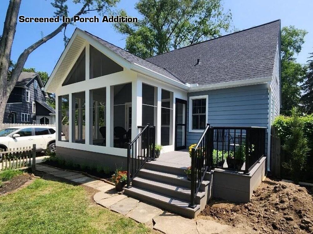 Screened porch with steps leading up to a light blue house, surrounded by green grass and trees.