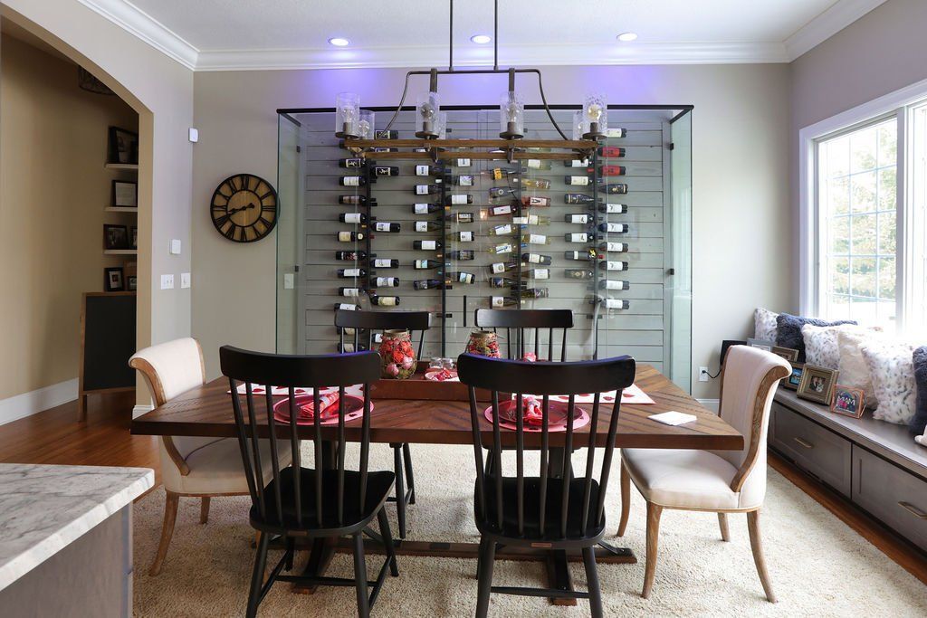 Dining room with a dark wood table, chairs, wine rack divider, and bench seating by a window.