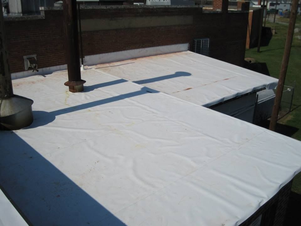 White flat roof on a building, with vent pipes and visible seams.