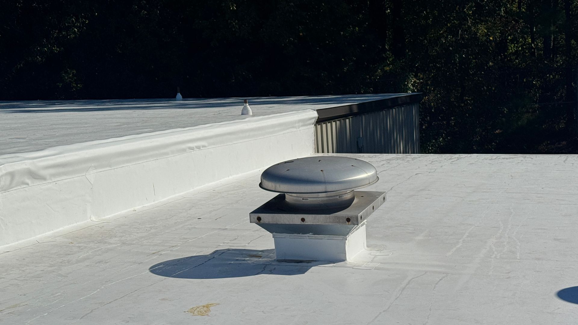 Ventilation cap on a white flat metal roof.
