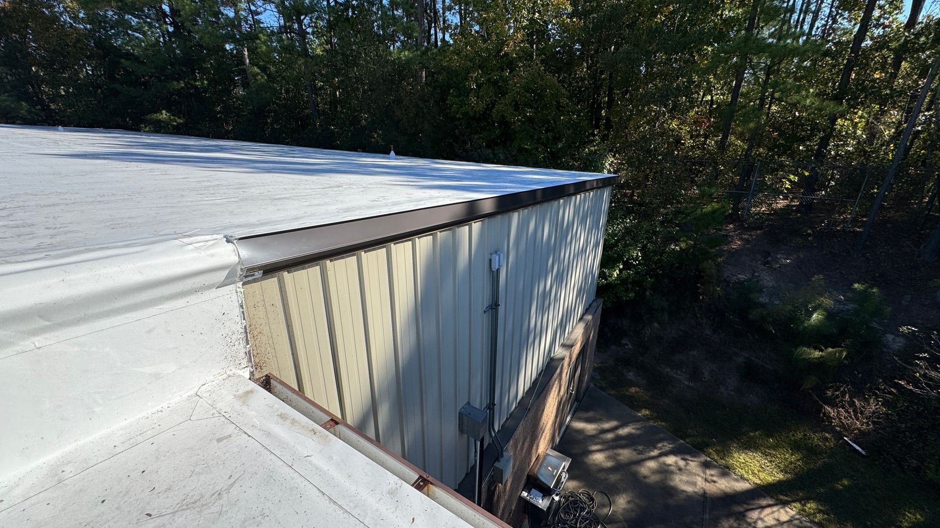 Flat white metal retrofit roof edge with metal trim.