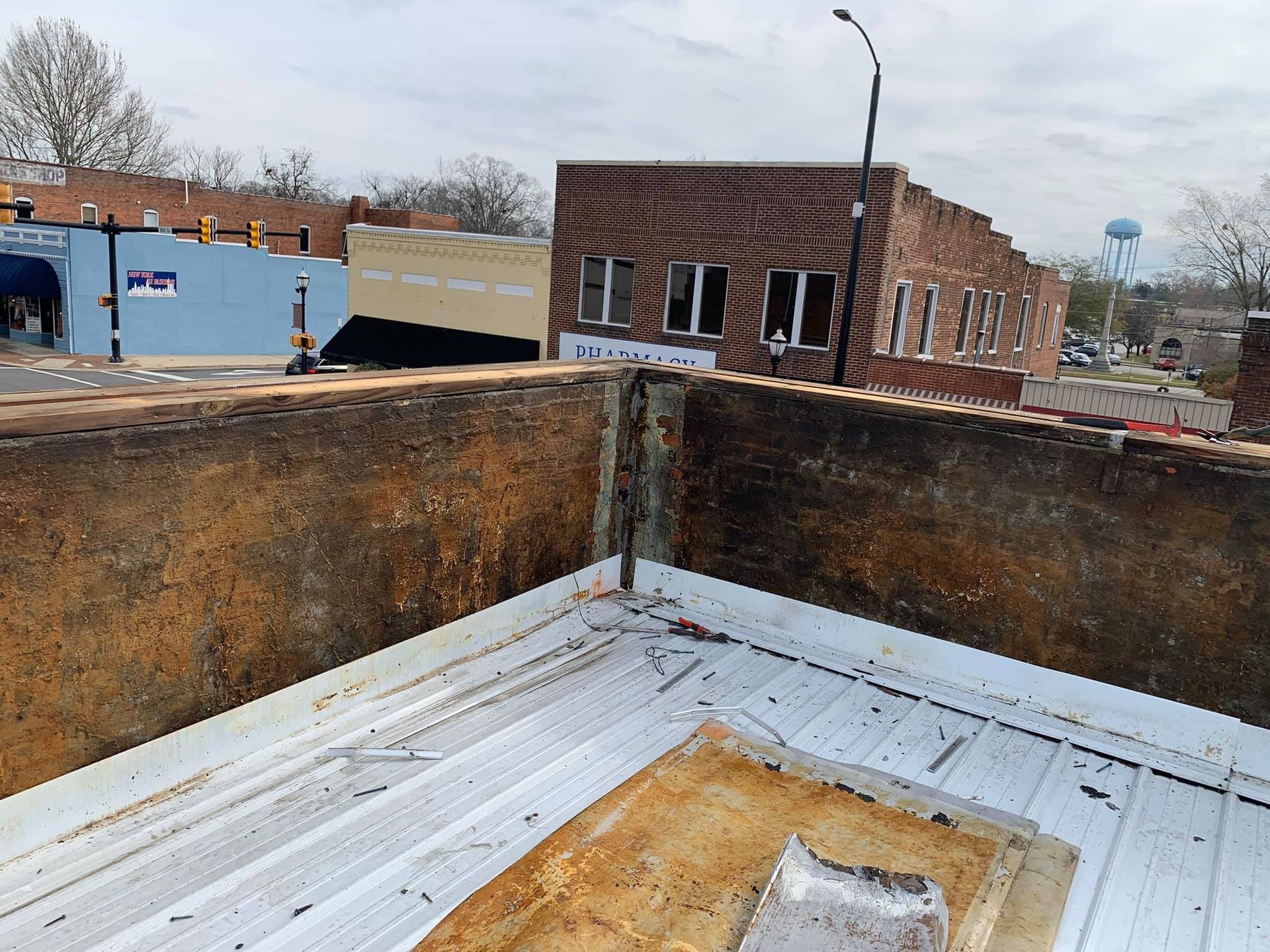 View from rooftop overlooking brick buildings in a small town; cloudy sky.