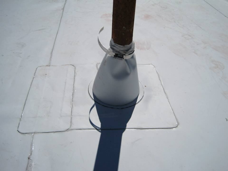 White roof with a metal pipe sealed with a flashing, and a patch beside it.