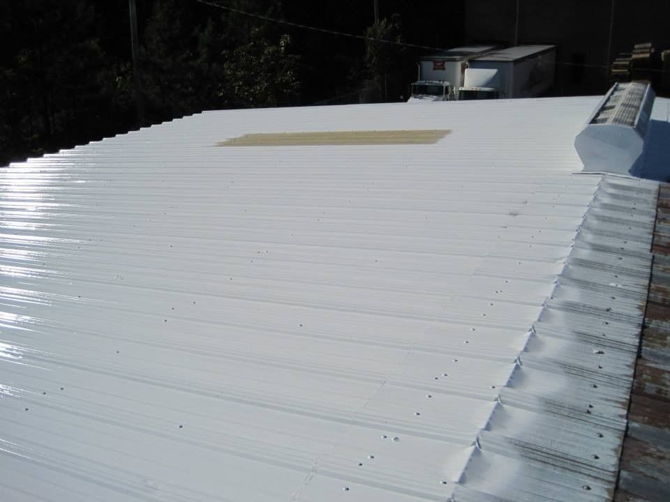 White-painted corrugated metal roof of a building with a skylight and a vent.