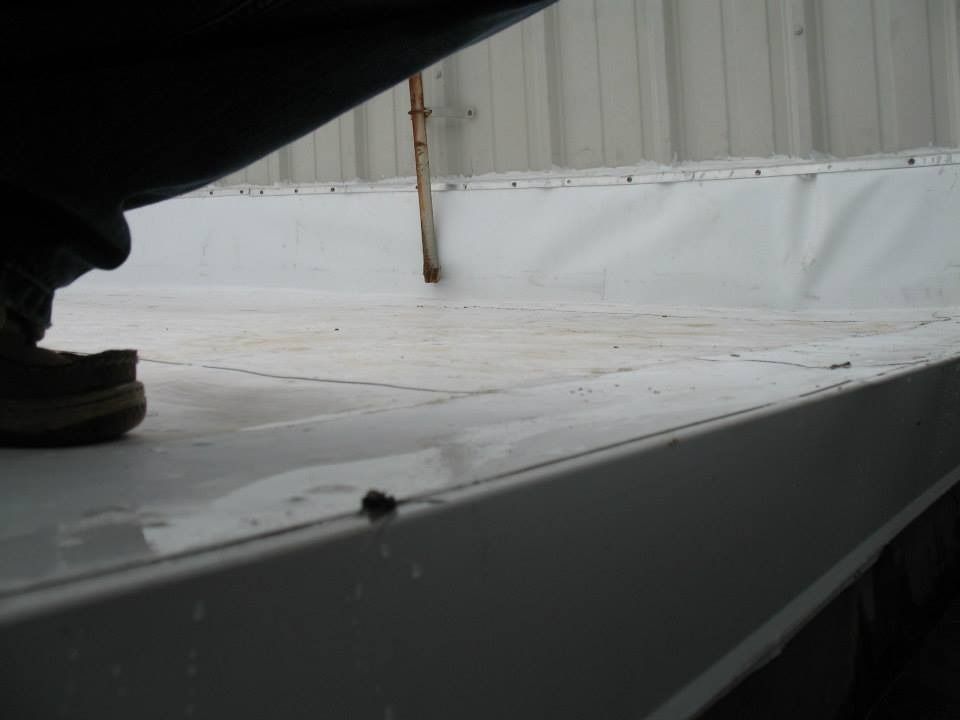 Person on a white metal roof with white vinyl lining around the edges.