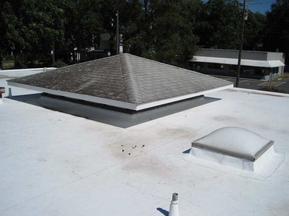A white flat roof with a square, pyramid-shaped skylight, and a smaller, rounded skylight.