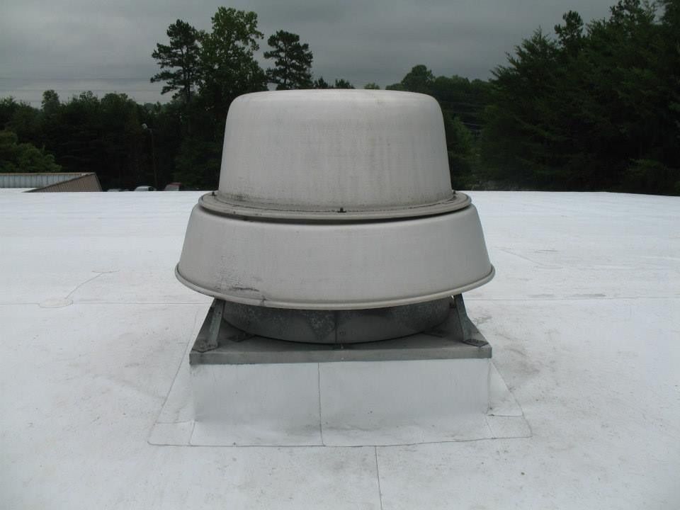 Large, white, rooftop ventilation unit on a flat roof, surrounded by white material.