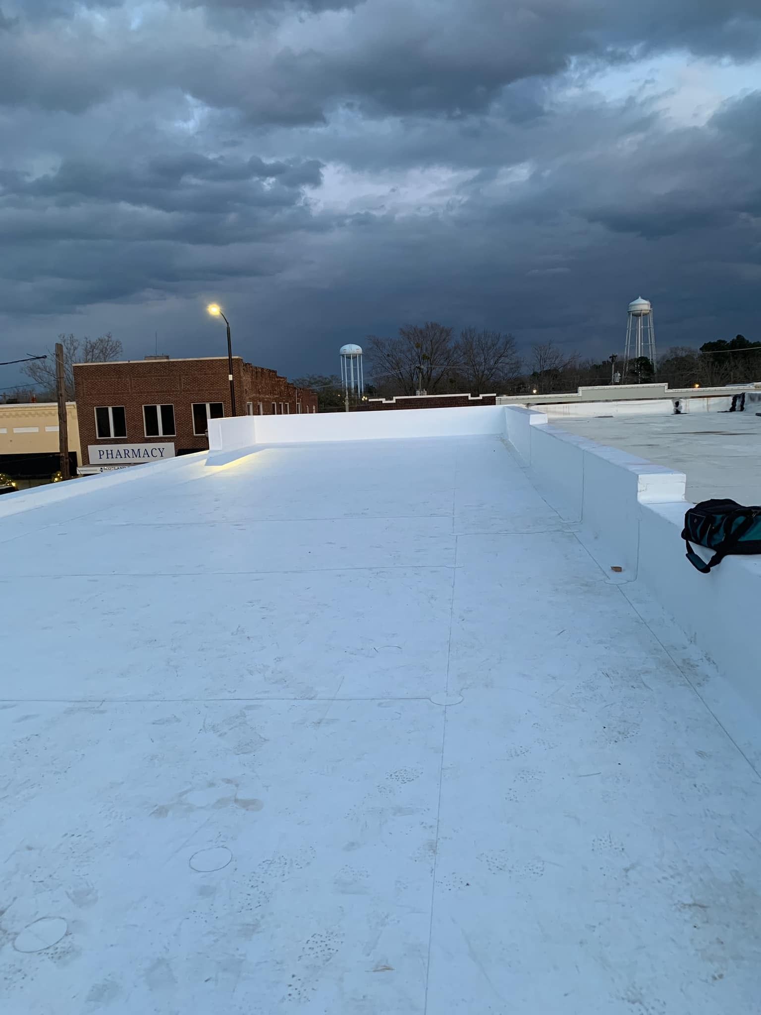 Flat white rooftop, buildings, water tower, and cloudy sky.
