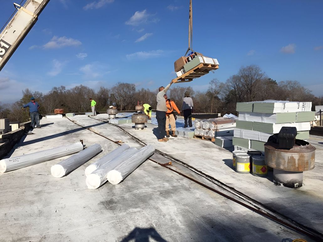 Workers installing roofing materials on a flat roof, crane lifting supplies.