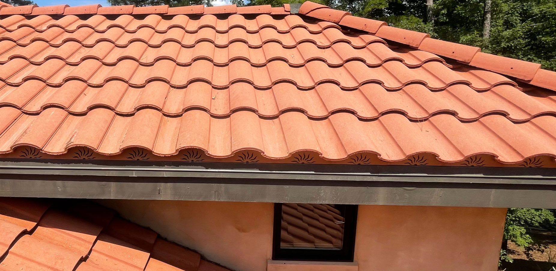 Terracotta tile roof with a dark gutter, the edge of a building in view.