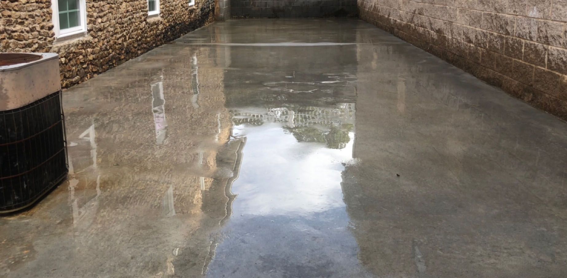 Wet concrete surface reflecting the sky and surrounding stone buildings.