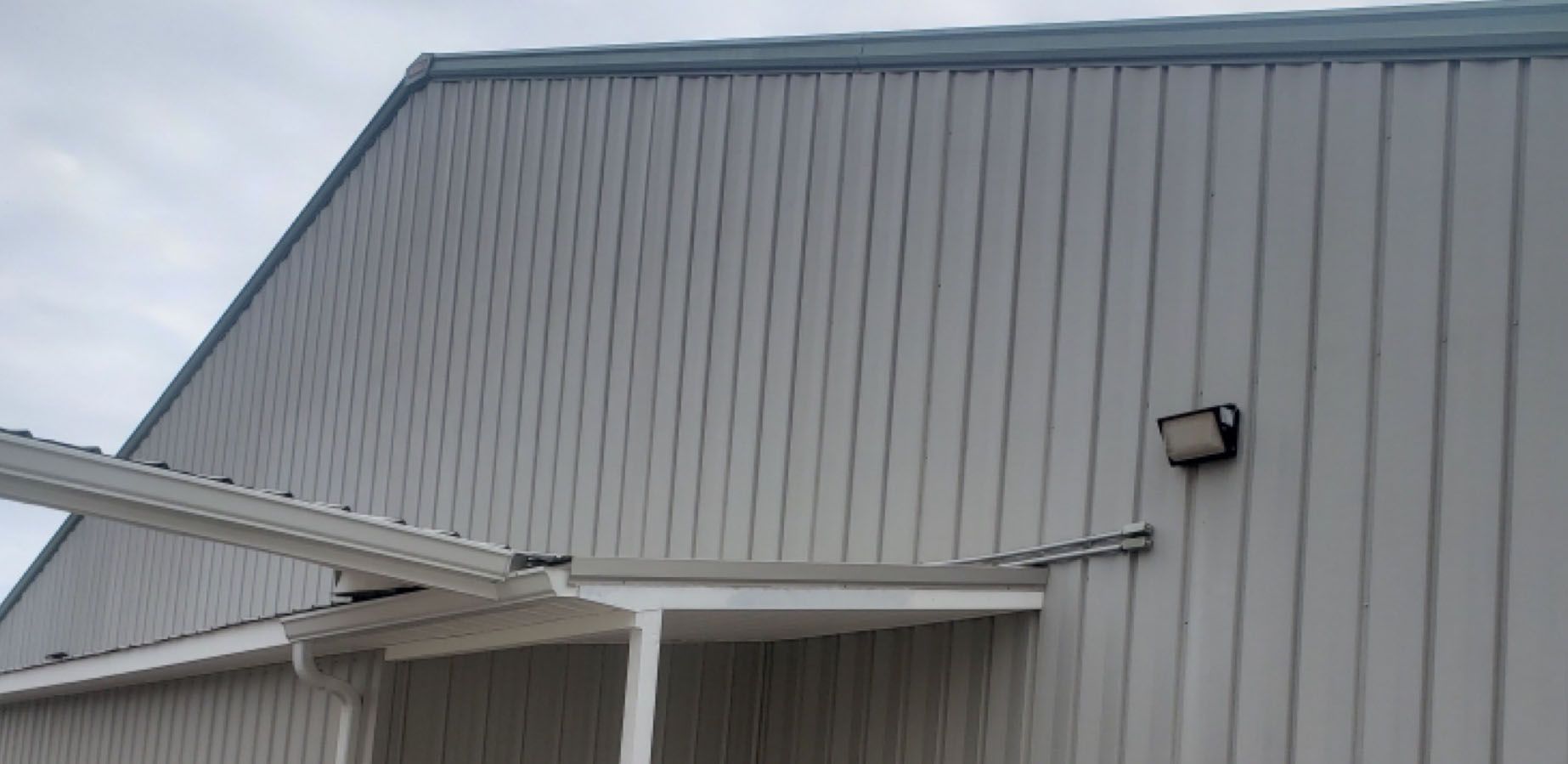 A light gray metal building under a cloudy sky.