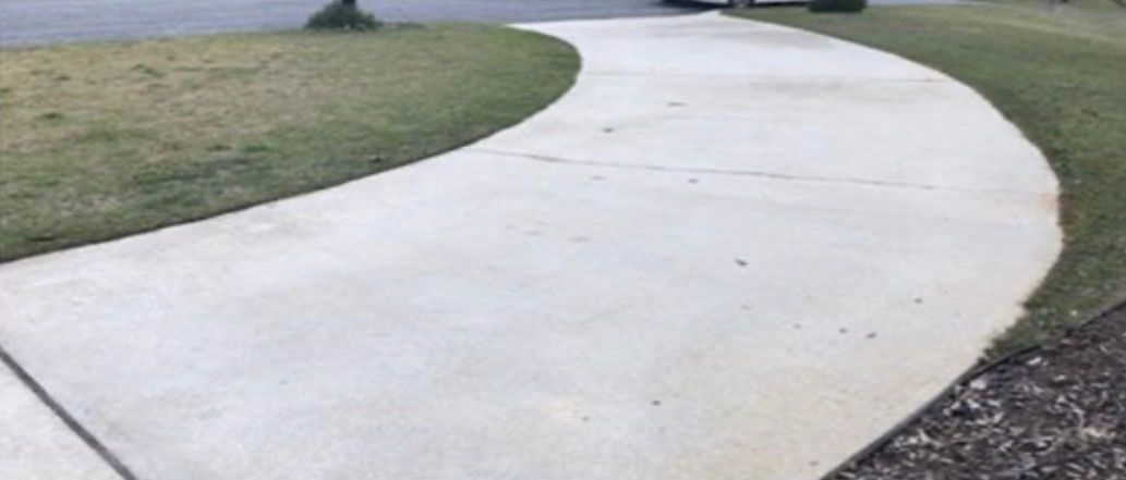 A concrete driveway curving through a grassy yard.