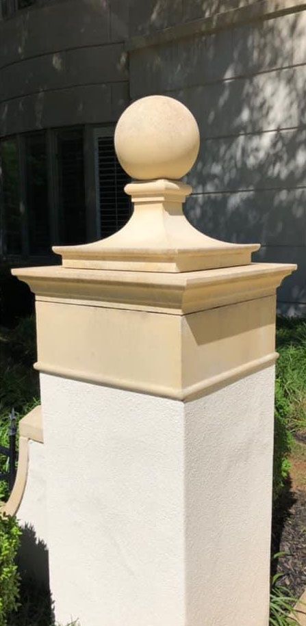 A tan pillar with a rounded top, ball-shaped ornament. The pillar is outdoors.