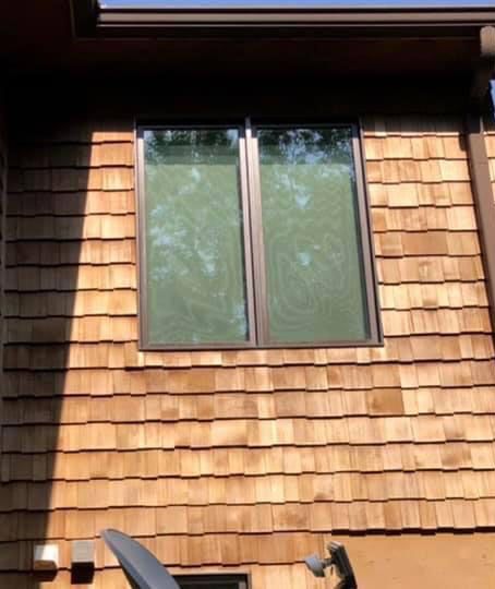 Brown cedar shake siding with a rectangular window.