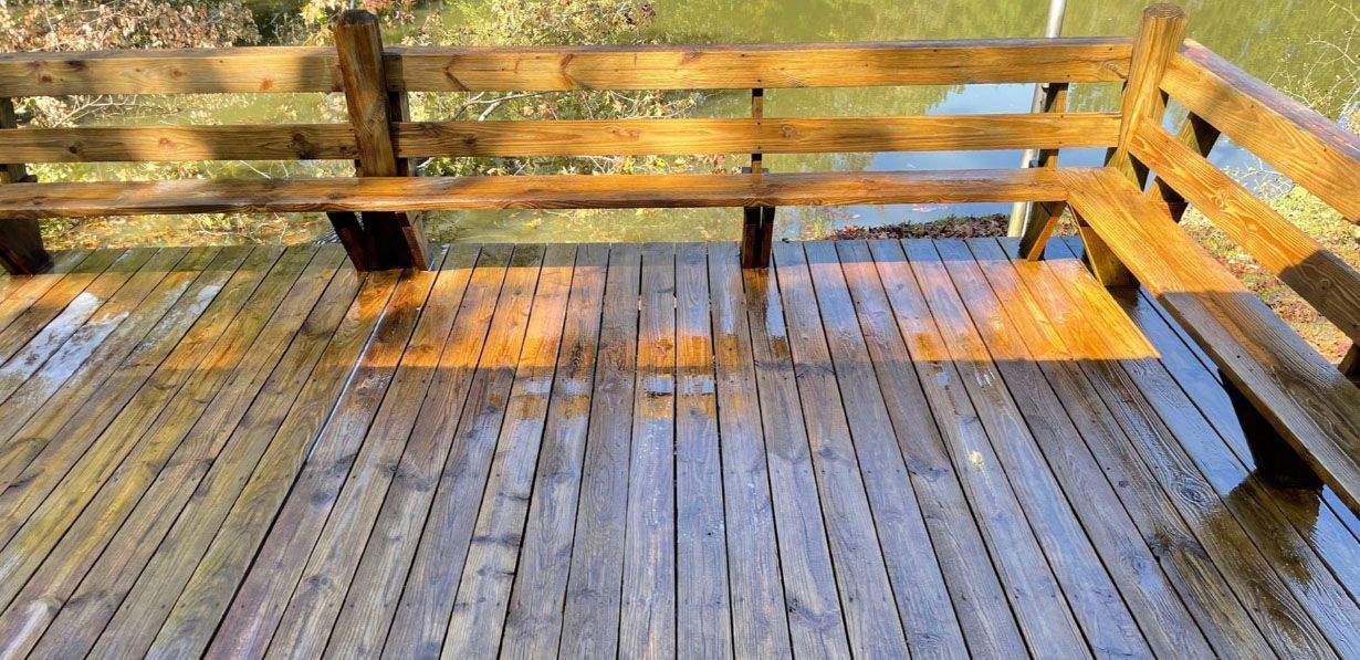 Wooden deck with built-in benches, wet from rain. Sunlight reflects across the surface.