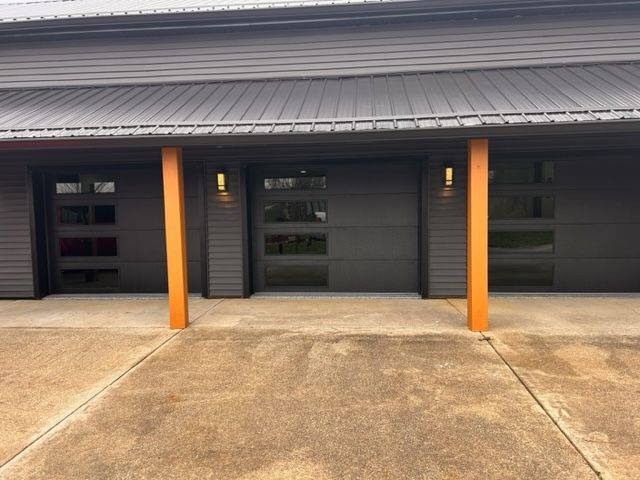 A black garage door with a wooden post in front of it.