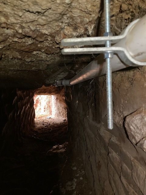 A metal pipe is hanging from the ceiling of a cave.