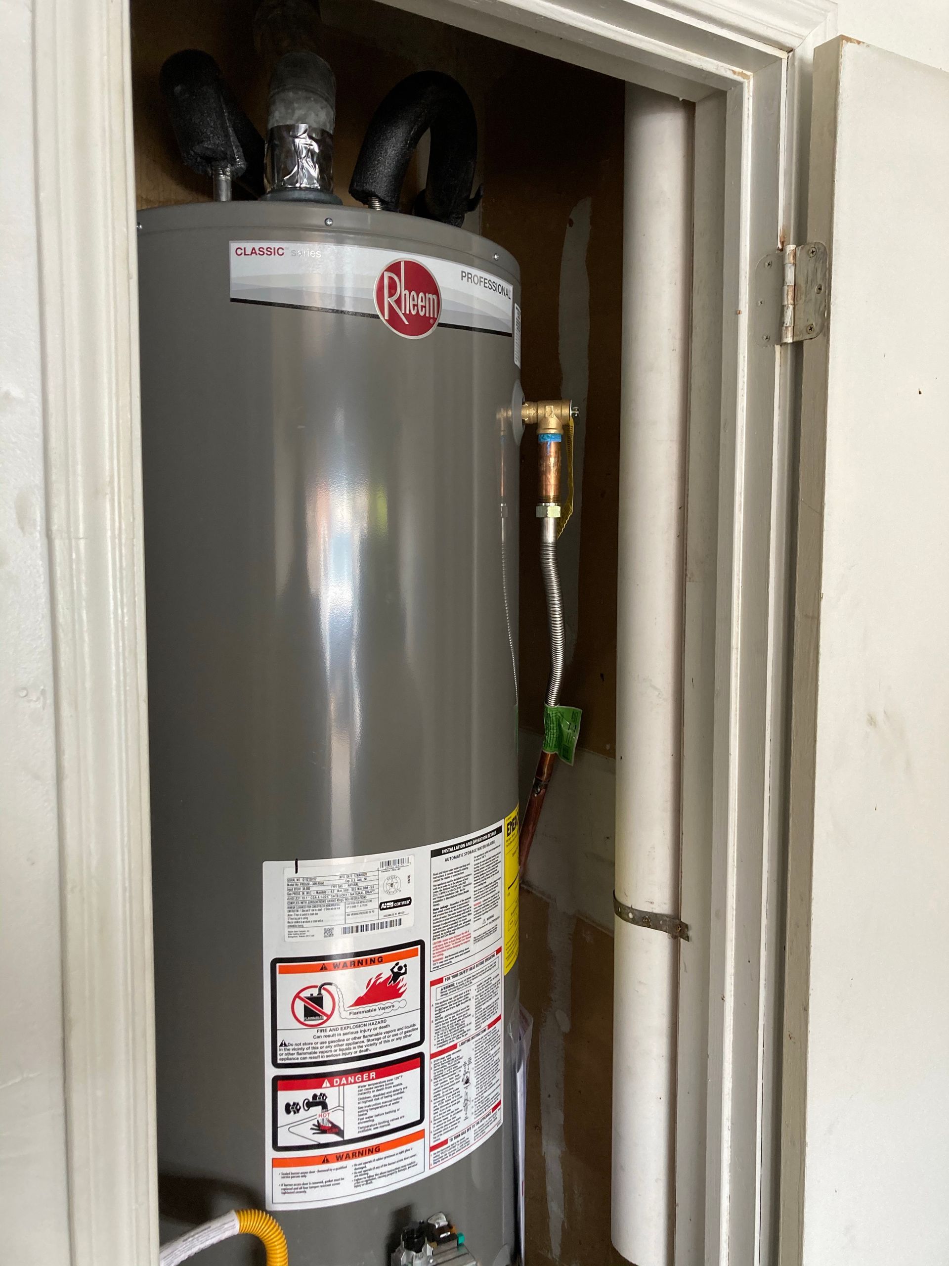 A water heater is sitting in a closet next to a door.