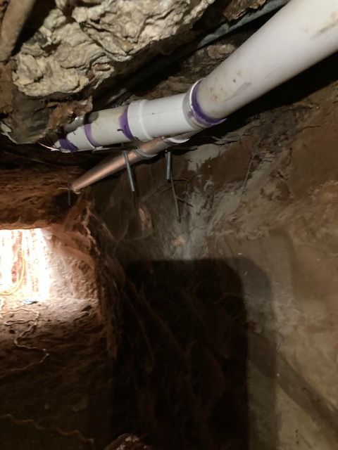 A white pipe is hanging from the ceiling in a dark room