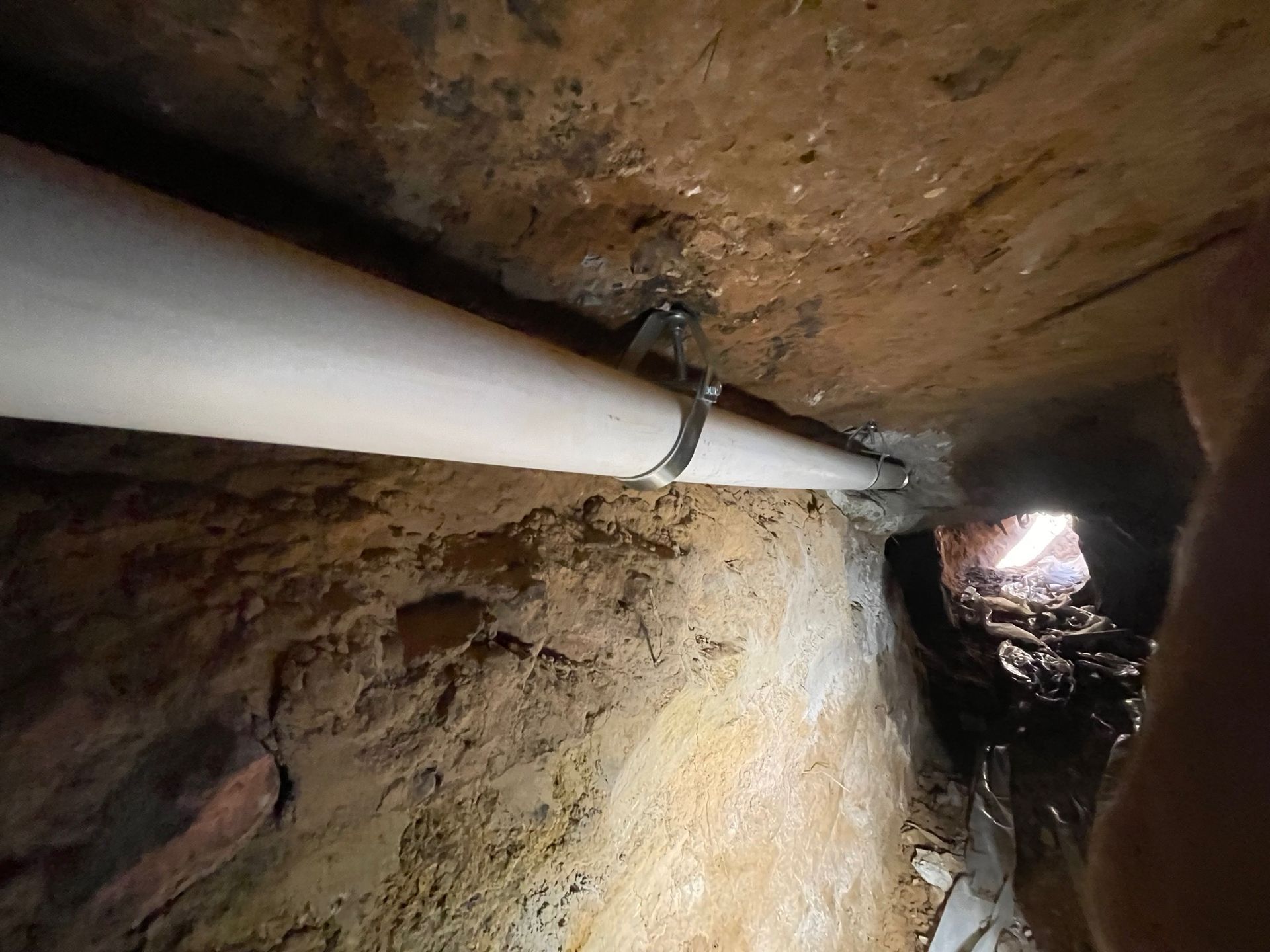 A white pipe is hanging from the ceiling of a cave.