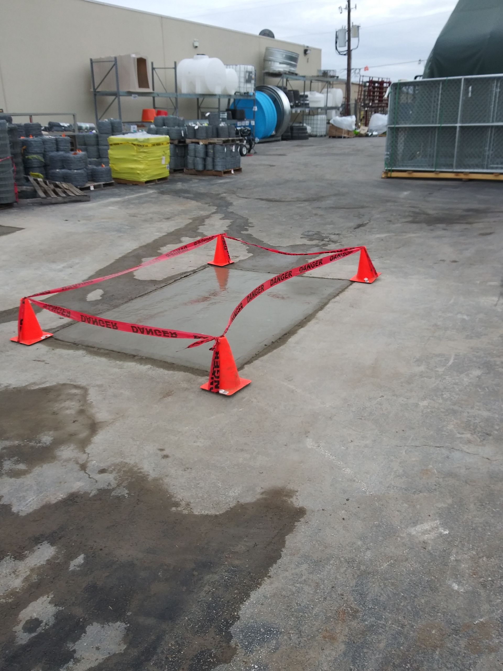 A concrete area with orange cones and red tape around it