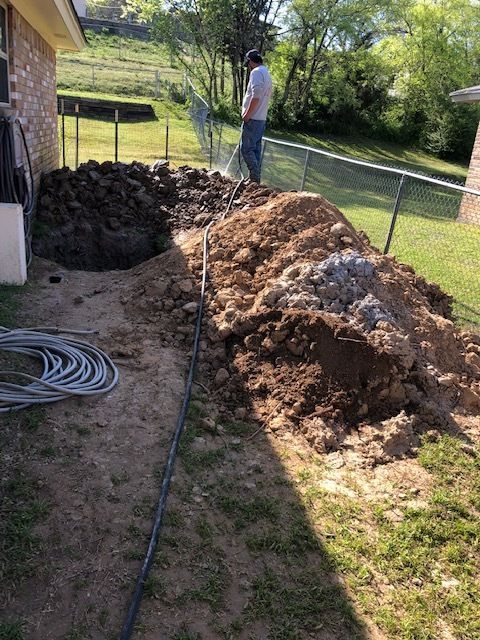 A man is digging a hole in the dirt in front of a house.