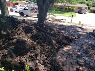A white truck is parked next to a pile of dirt.