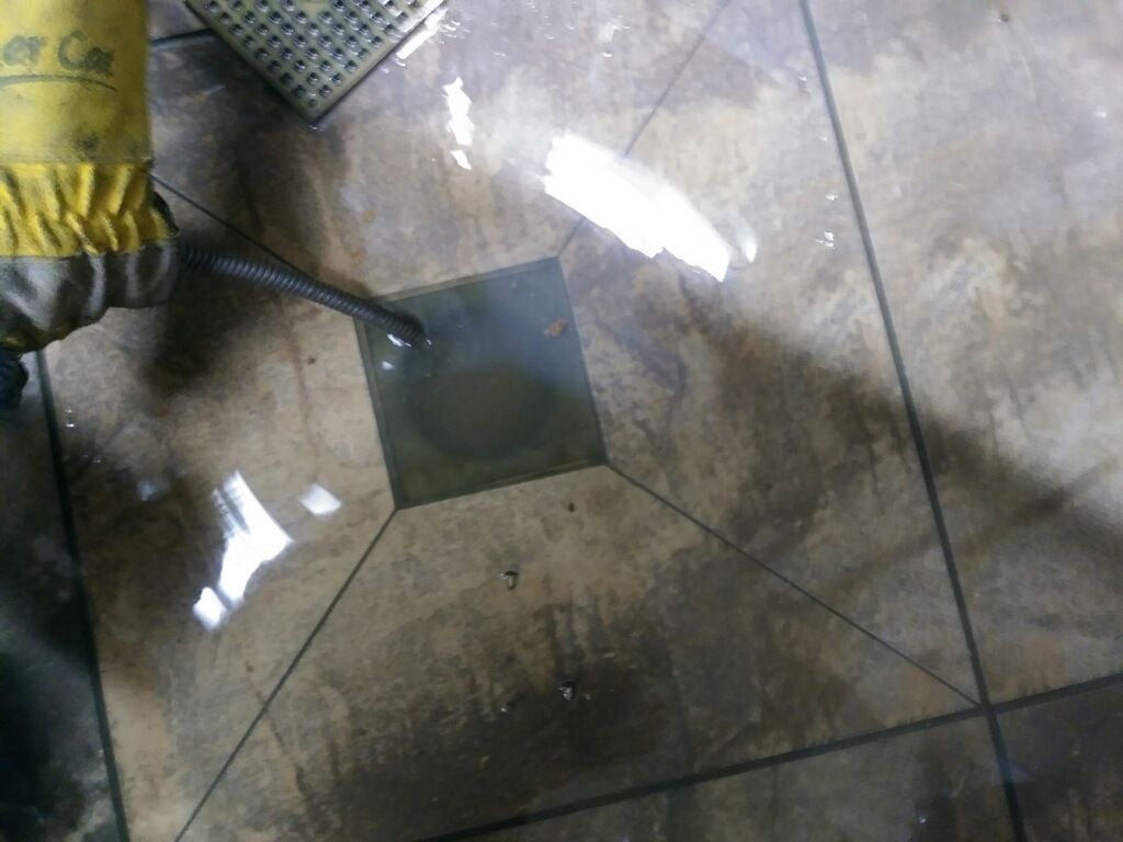 A person wearing a yellow glove is cleaning a tile floor