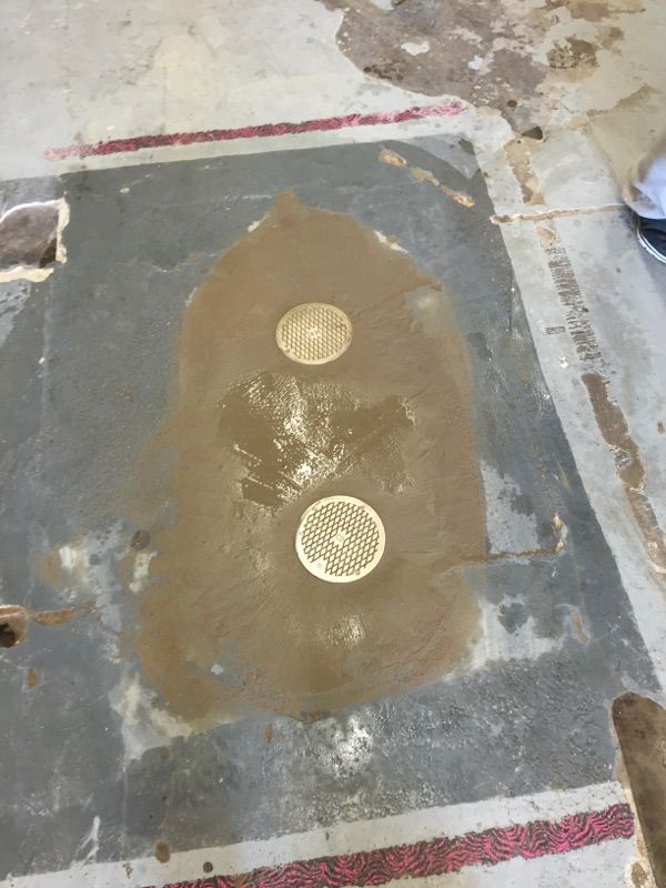 A hole in the floor with two drains in it.