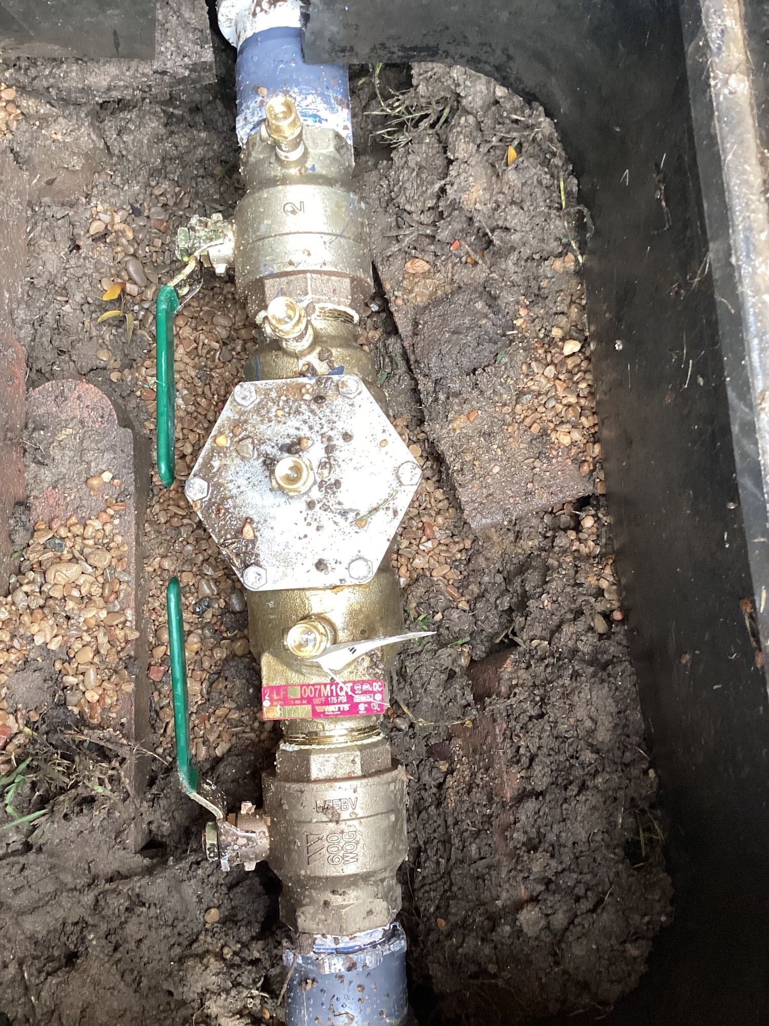 A close up of a water pipe in the dirt.