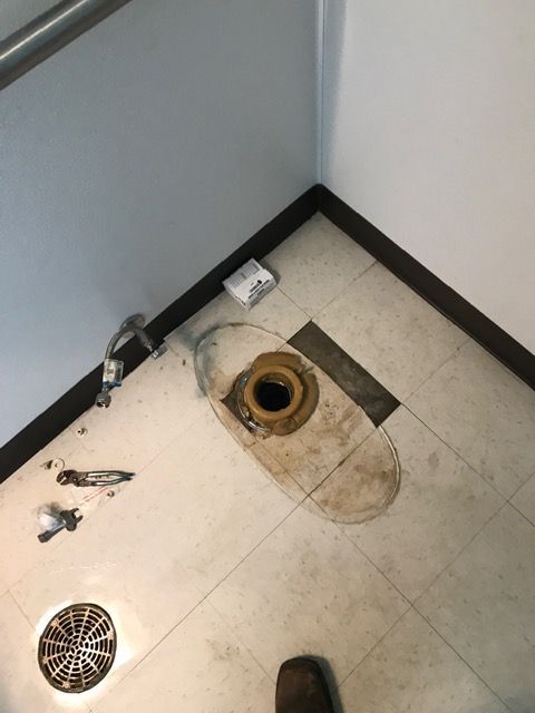 A person is standing in a bathroom next to a toilet.