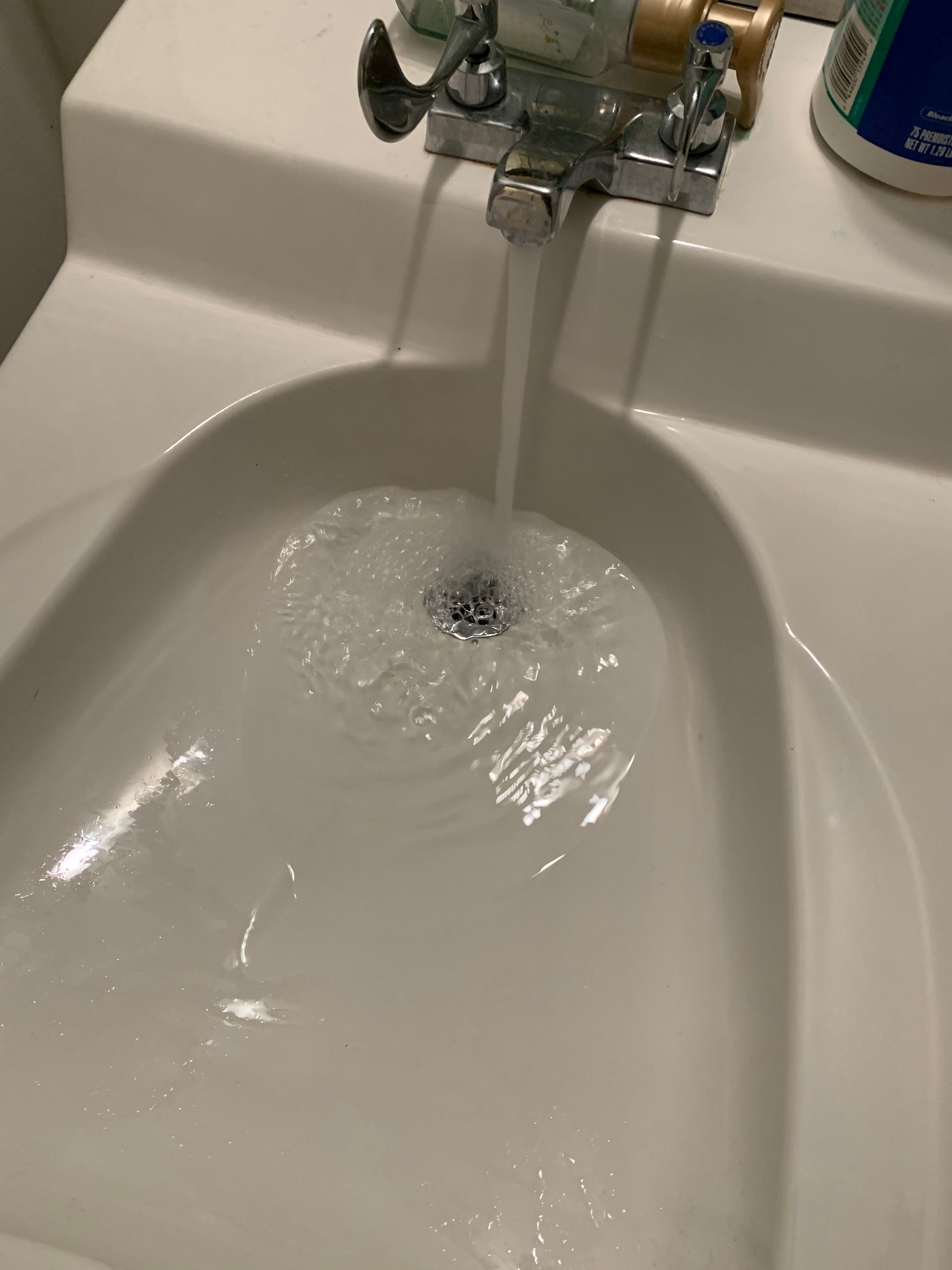 A bathroom sink with water coming out of the faucet.