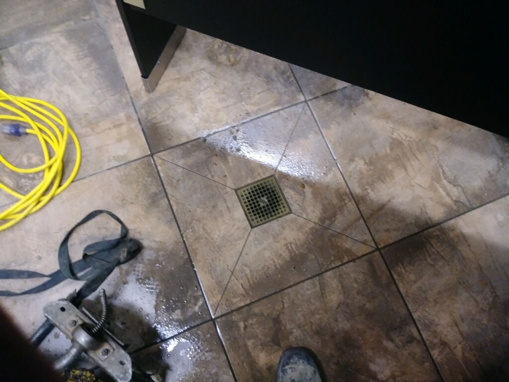 A person is standing on a tiled floor next to a yellow cord.