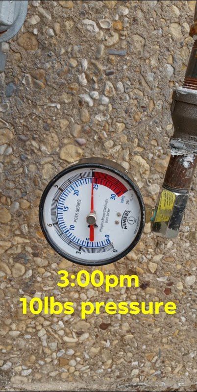 A pressure gauge is sitting on a rocky surface.