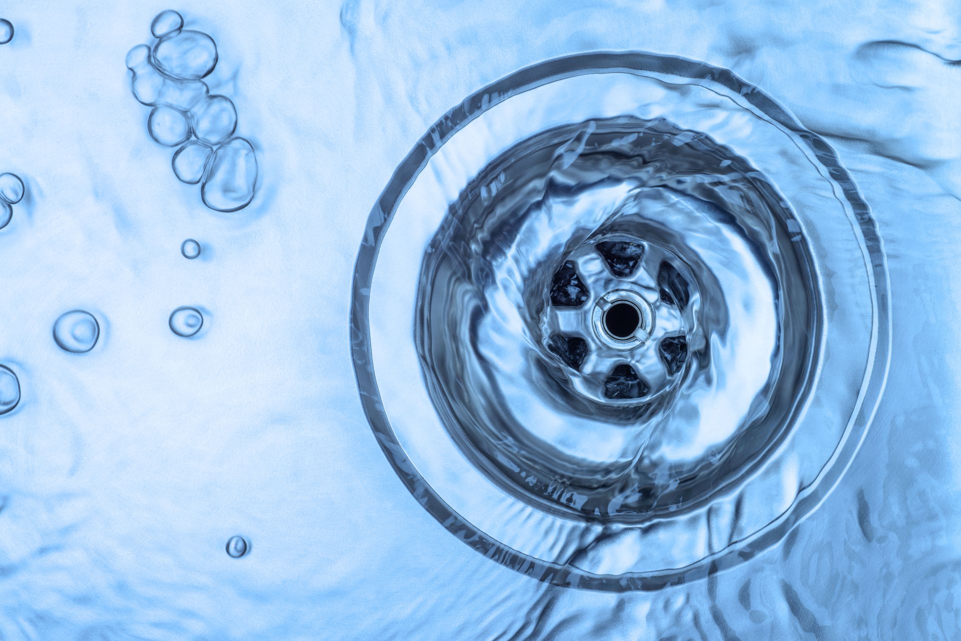 A close up of a sink drain with water running down it.