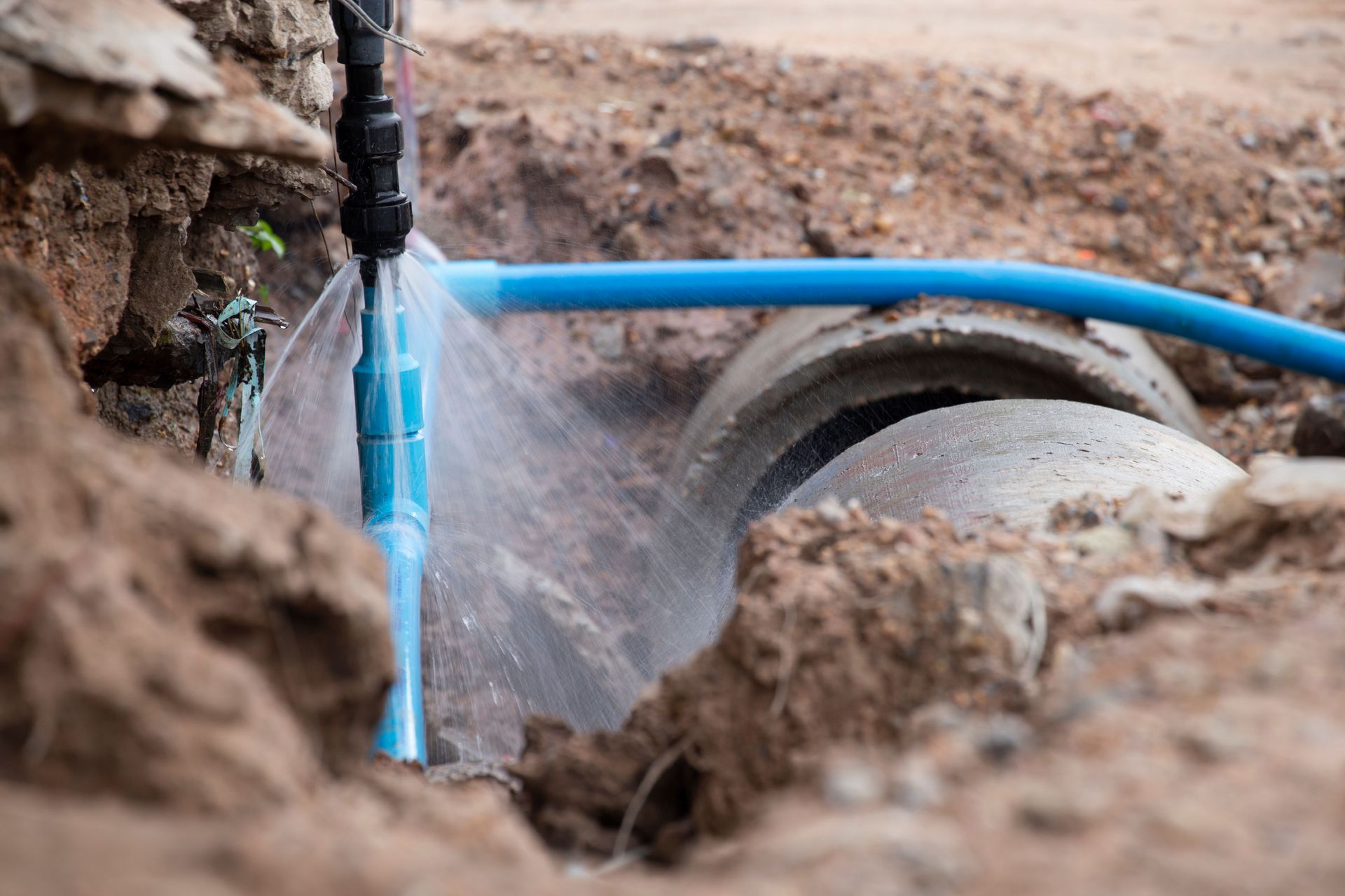 A water pipe is broken in the ground and water is coming out of it.