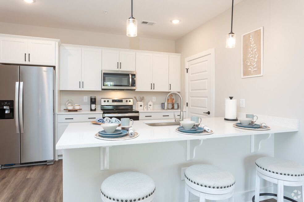a kitchen with white cabinets, stainless steel appliances, a refrigerator, and a sink