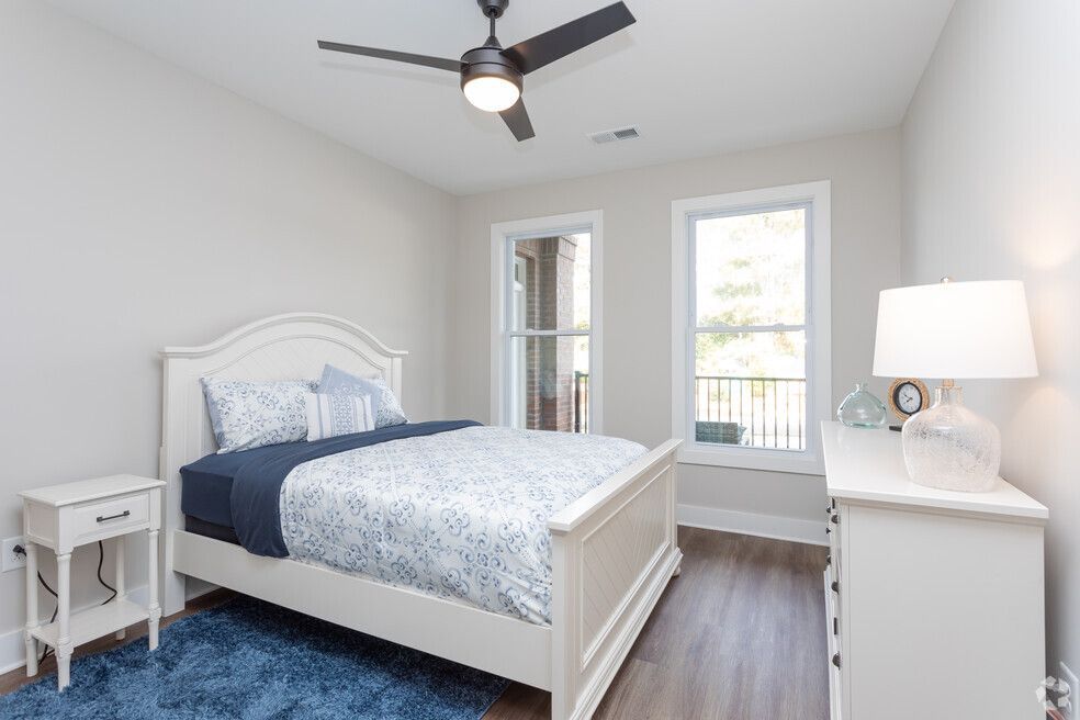 a bedroom with a bed, dresser, nightstand, and ceiling fan