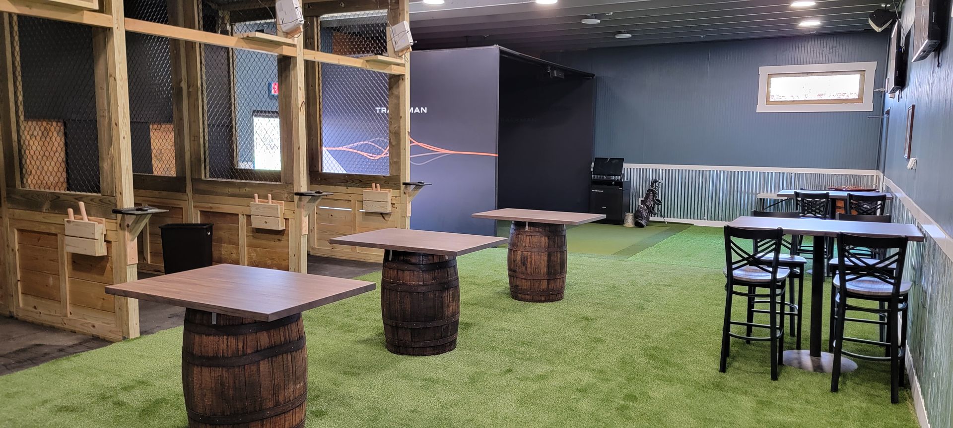 a room with tables and chairs and barrels on the grass