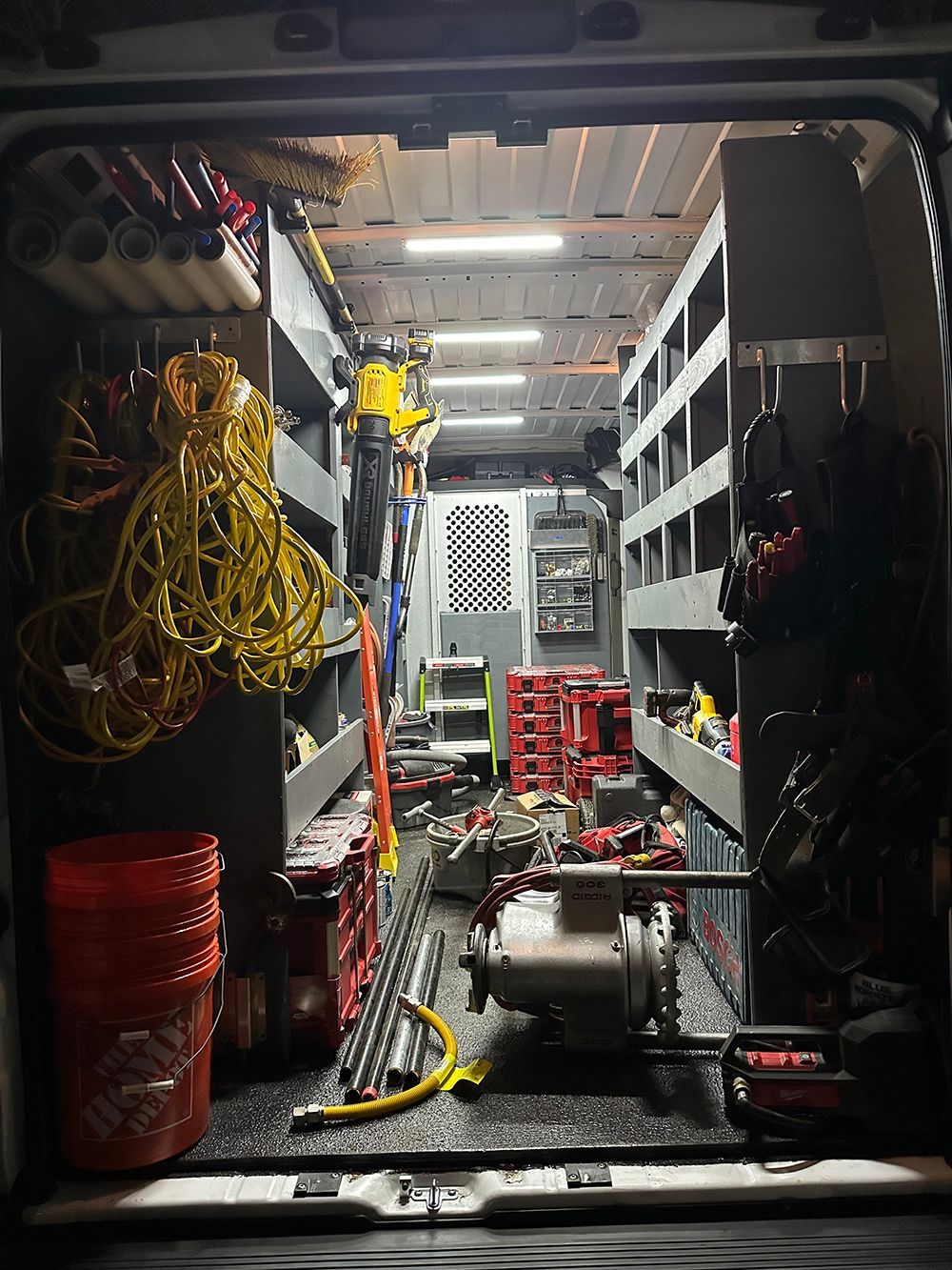 Inside of a work van, tools, shelves, and equipment are visible.