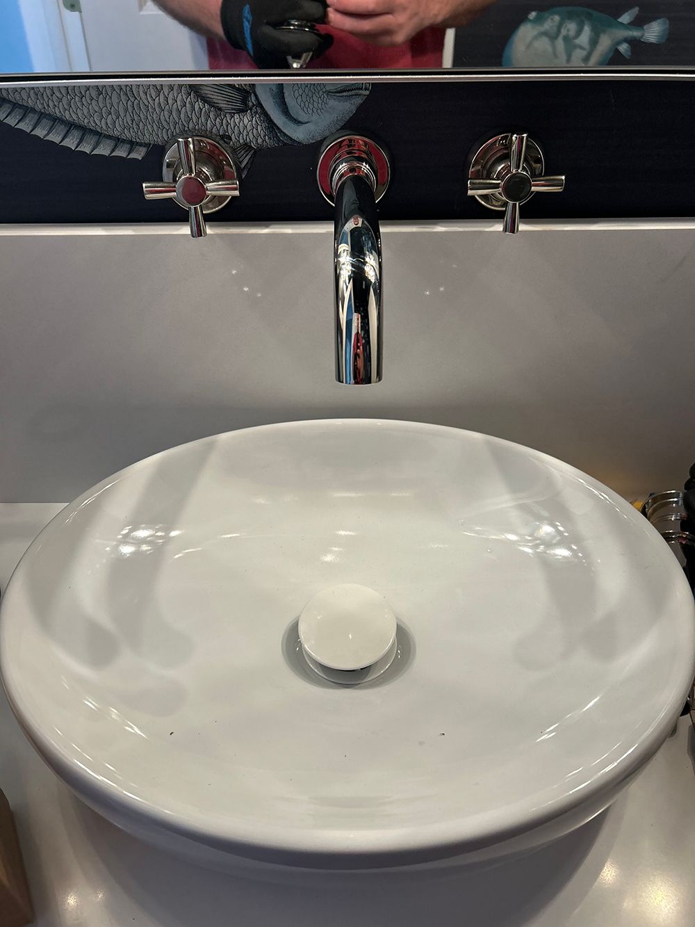White oval sink with chrome faucet and handles.