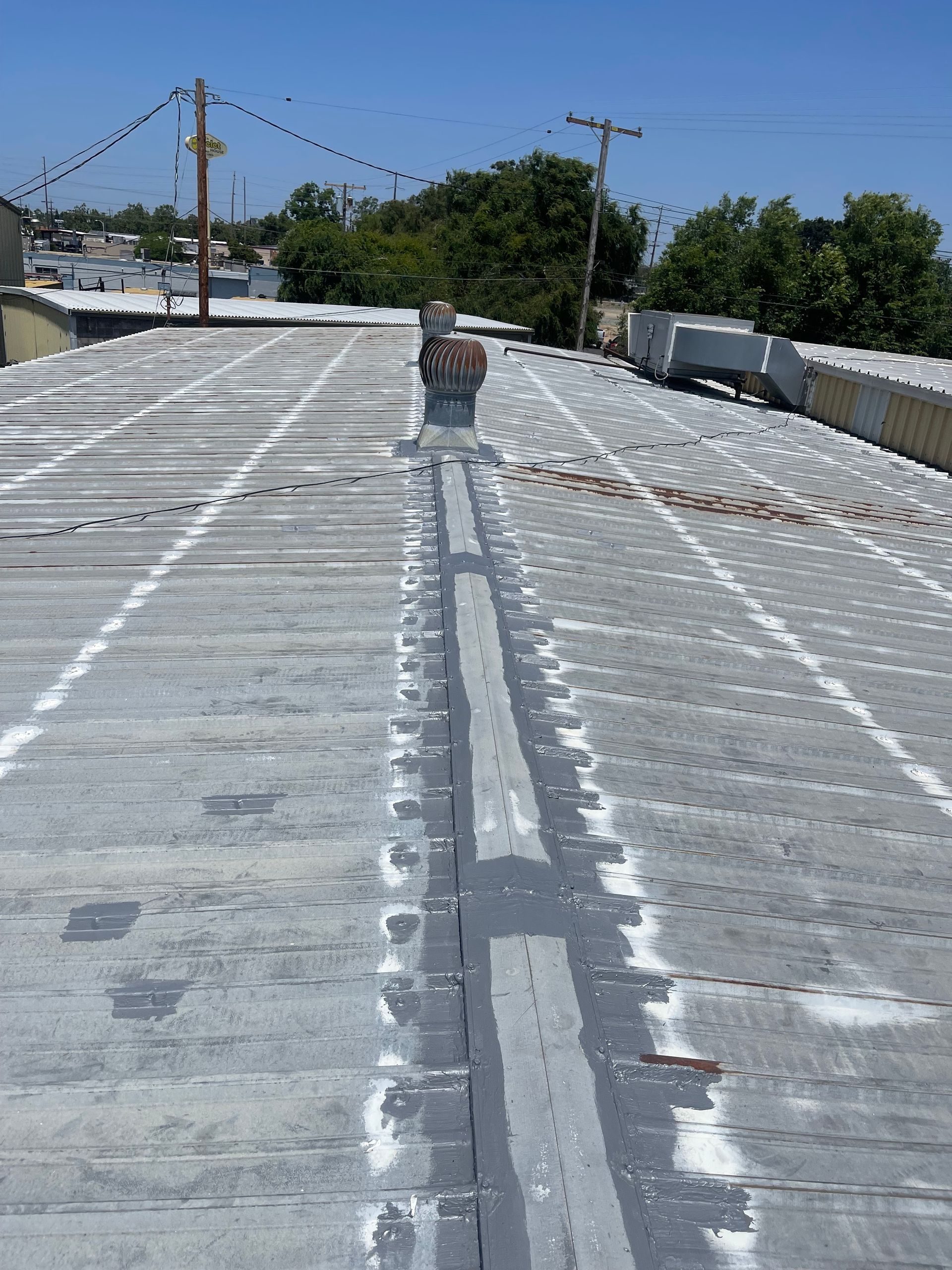 Rooftop under construction with a worker near the center and white waterproofing lines stretching into the distance